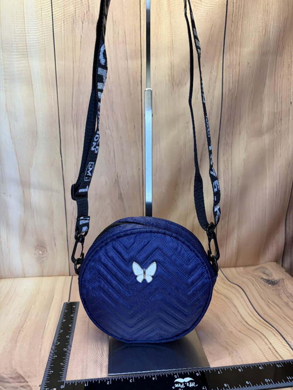 Small navy blue quilted round crossbody bag featuring a distinct white butterfly